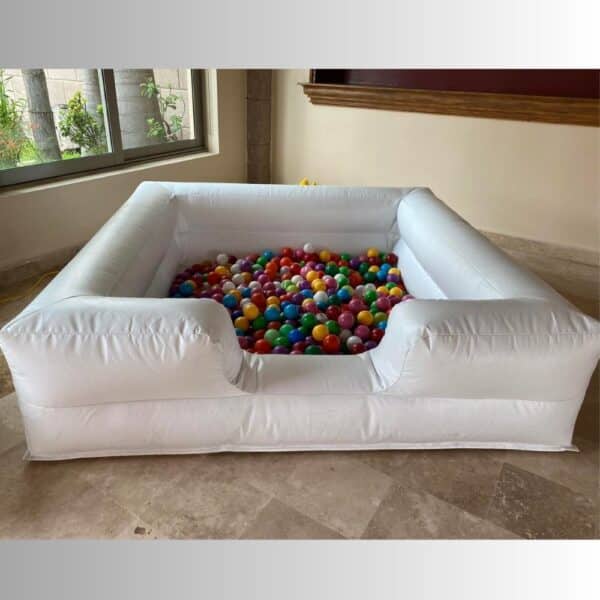 Alberca inflable blanca llena de pelotas multicolor colocada en interior con piso de mármol