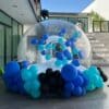 Burbuja inflable para jardín decorada con globos de colores llamativos, colocada dentro de una sección al aire libre de una casa.