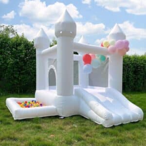 Castillo inflable blanco con cuatro torres, resbaladilla frontal y alberca de pelotas, decorado con globos pastel