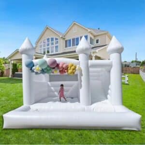 Castillo inflable blanco con decoración floral y área tipo alberca y una niña jugando en el.