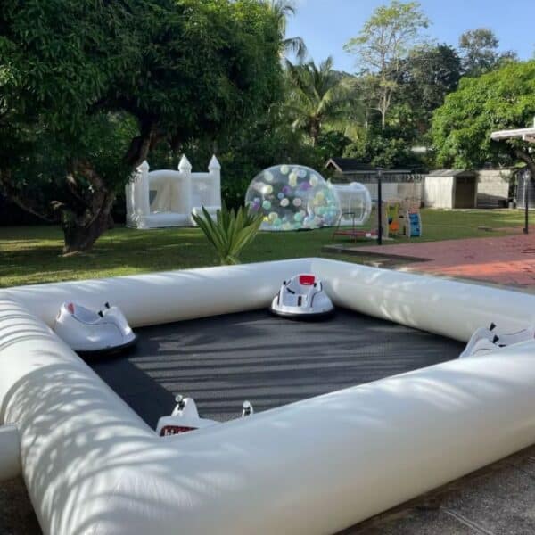 Pista inflable para bumper cars blancos en exterior con castillo inflable y burbuja decorativa al fondo.